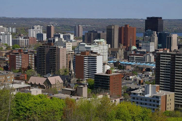 A cityscape view of Hamilton, Ontario, with buildings and trees, taken from an elevated position.